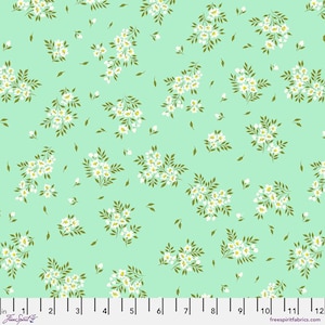 May include: A fabric with a repeating floral pattern. Clusters of white flowers with yellow centers and green leaves are scattered across a light green background. The fabric has a ruler along the bottom edge with measurements in inches.