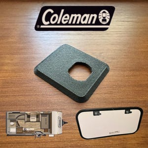 May include: A black square-shaped plastic vent cover with a round hole in the center. The vent cover is designed for use with a Coleman camper.