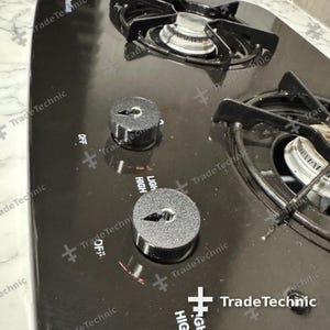 May include: A black glass stovetop featuring two circular burners with black metal grates and two textured black control knobs. The surface is printed with white text including the words OFF and HIGH, indicating the burner settings.