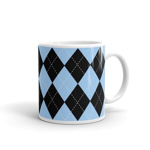 May include: A white ceramic mug with a black and light blue argyle pattern. The mug has a white handle.
