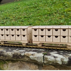 May include: A wooden train with 24 numbered compartments, each compartment is a drawer. The train is on a track and the compartments are numbered 1 through 24.