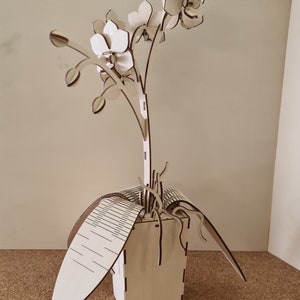 Peut inclure: Une sculpture d'orchid&eacute;e en bois avec trois fleurs et un pot. La sculpture est en bois d&eacute;coup&eacute; au laser et a une finition en bois naturel.
