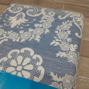 May include: A blue and white patterned fabric with a floral design. The fabric is wrapped around a cushion or pillow.