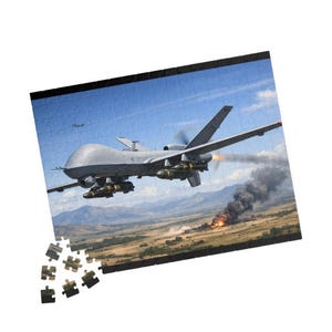 May include: A jigsaw puzzle featuring a gray military drone in flight over a landscape with a fire and smoke. The puzzle is partially assembled, with some pieces scattered. The sky is blue.