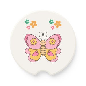 May include: A white car coaster featuring a colorful butterfly design. The butterfly has pink and yellow wings with flower accents. Two sets of small flowers in orange, pink, and green are above the butterfly. The coaster has a small notch for easy removal.
