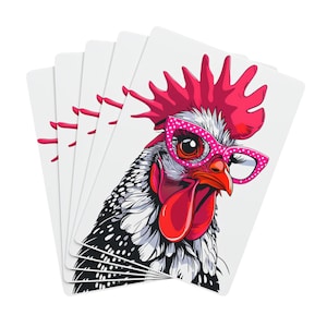 May include: A stack of playing cards featuring a cartoon rooster wearing pink polka dot glasses. The rooster has a red comb and wattle, with black and white speckled feathers. The cards are white.