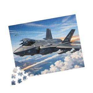 May include: A jigsaw puzzle featuring a detailed illustration of a gray F-35 fighter jet soaring through a blue sky with clouds. The jet has the text "AF 812" on its tail. Some puzzle pieces are separate.