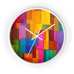 May include: A round wall clock with a white frame. The clock face features a colorful abstract design of rectangular shapes in shades of red, orange, yellow, green, blue, purple, and brown. White clock hands indicate the time.
