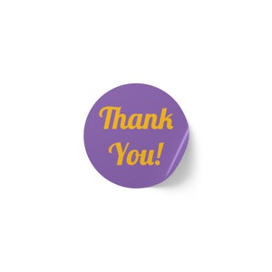 Puede incluir: Pegatina redonda de color morado con el texto "¡Gracias!" en amarillo.