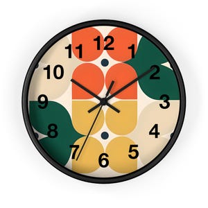 May include: Round wall clock with a black frame and a retro design. The clock face features orange, green, and yellow geometric shapes against a cream background. Black hands and numerals complete the design.