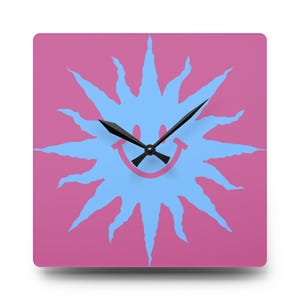 May include: Square wall clock with a pink background and a light blue sun design. The sun has a smiling face in the center and black clock hands. The clock is a decorative item for a bedroom or living room.