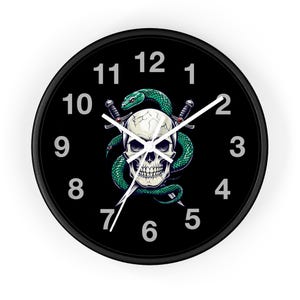 Può includere: Orologio da parete rotondo nero con un design a teschio e serpente verde. Il teschio è bianco con una superficie screpolata e il serpente è avvolto attorno ad esso. Due pugnali incrociati sono dietro il teschio. L'orologio ha numeri e lancette bianche.