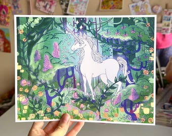Peut inclure: Une licorne blanche avec une corne dorée se tient dans une forêt verdoyante luxuriante avec des fleurs violettes et roses. L'arrière-plan est une aquarelle de vert, bleu et violet.