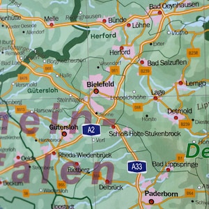 May include: A map of Germany with the cities of Bielefeld, G&uuml;tersloh, Detmold, Paderborn, and Herford highlighted. The map is green with yellow roads and black text.
