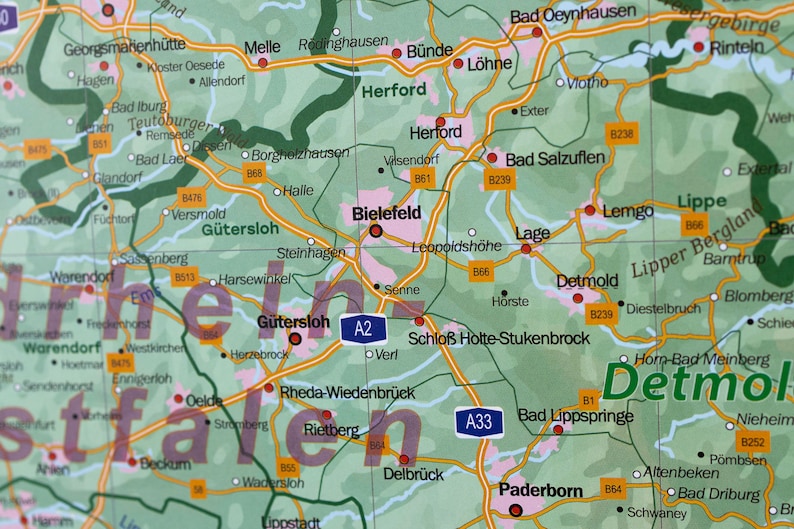 May include: A map of Germany with the cities of Bielefeld, G&uuml;tersloh, Detmold, Paderborn, and Herford highlighted. The map is green with yellow roads and black text.