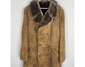 Peut inclure: Un manteau en daim marron avec un col et des revers en fausse fourrure. Le manteau croisé a quatre boutons et deux poches. Le manteau est suspendu à un cintre en bois.