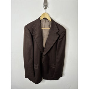 May include: A brown blazer with a brown and white plaid lining. The blazer has a single button closure and two pockets.
