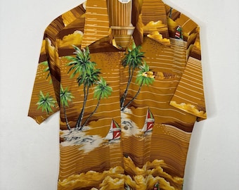 Peut inclure: Une chemise hawaïenne marron et jaune avec un imprimé de palmiers et de voiliers. La chemise a un col boutonné et des manches courtes. L'étiquette indique "Made in Hawaii".