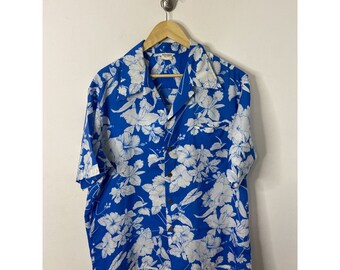 Peut inclure: Une chemise à manches courtes bleue avec un motif floral blanc. La chemise a un devant boutonné et un col.
