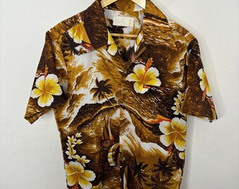 Peut inclure: Une chemise à manches courtes marron et blanche avec un imprimé tropical représentant des palmiers, des vagues et des fleurs d'hibiscus jaunes.