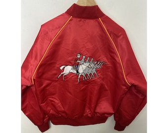 May include: Red satin bomber jacket with a yellow trim and an embroidered design of a person riding a horse with other people following behind on horses.