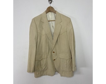 May include: A beige blazer with two pockets on the front and two buttons. The blazer has a notched lapel and is made of a textured fabric.