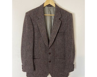 May include: A brown tweed blazer with a single-breasted closure and two front pockets. The blazer has a herringbone pattern and a subtle sheen.