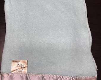 May include: A light blue blanket with a satin trim. The blanket has a soft, plush texture and a label that reads "Chatham Purrey Blanket". The satin trim is a light gray color.