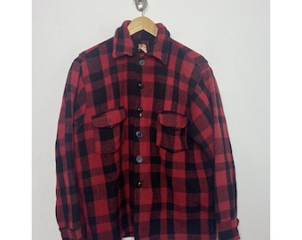 May include: A red and black plaid flannel shirt with a button-up front and two flap pockets.