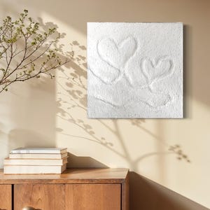 Puede incluir: Lienzo blanco texturizado con dos formas de corazón en relieve.