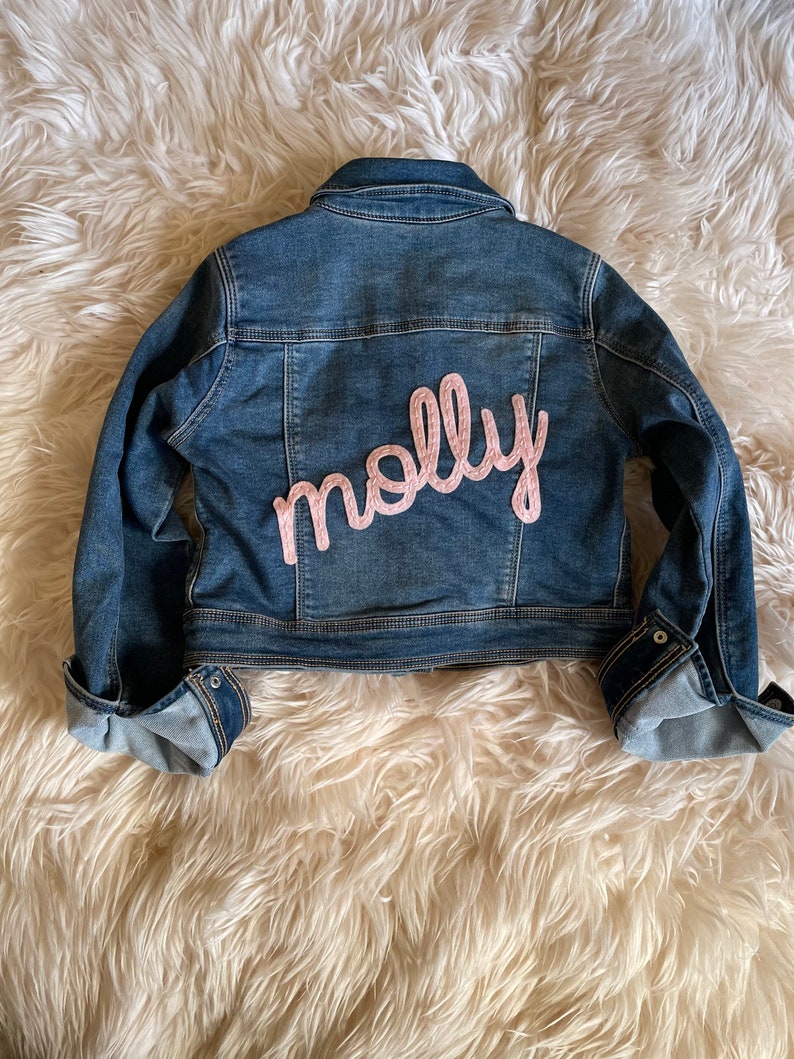 Personalized jean jacket with hand embroidery. 
Molly with special request all lower case lettering. Baby pink felt with baby pink thread.