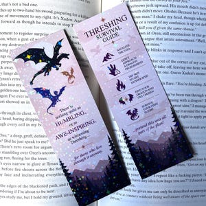 May include: Two rectangular bookmarks with a lavender and dark purple gradient background featuring silhouettes of dragons, pine trees, and stars. One bookmark displays the text Threshing Survival Guide with icons, while the other features the quote There is nothing quite as HUMBLING, or as AWE-INSPIRING, as witnessing Threshing.