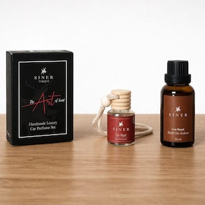 Könnte beinhalten: Eine schwarze Schachtel mit dem Text "The Art of Scent" und "Handmade Luxury Car Perfume Set" neben einer kleinen Glasflasche mit Holzverschluss und einer größeren braunen Flasche.