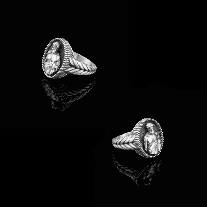 Puede incluir: Un anillo de plata con un dise&ntilde;o detallado de la cabeza de un hombre en un marco ovalado. La banda del anillo est&aacute; trenzada.