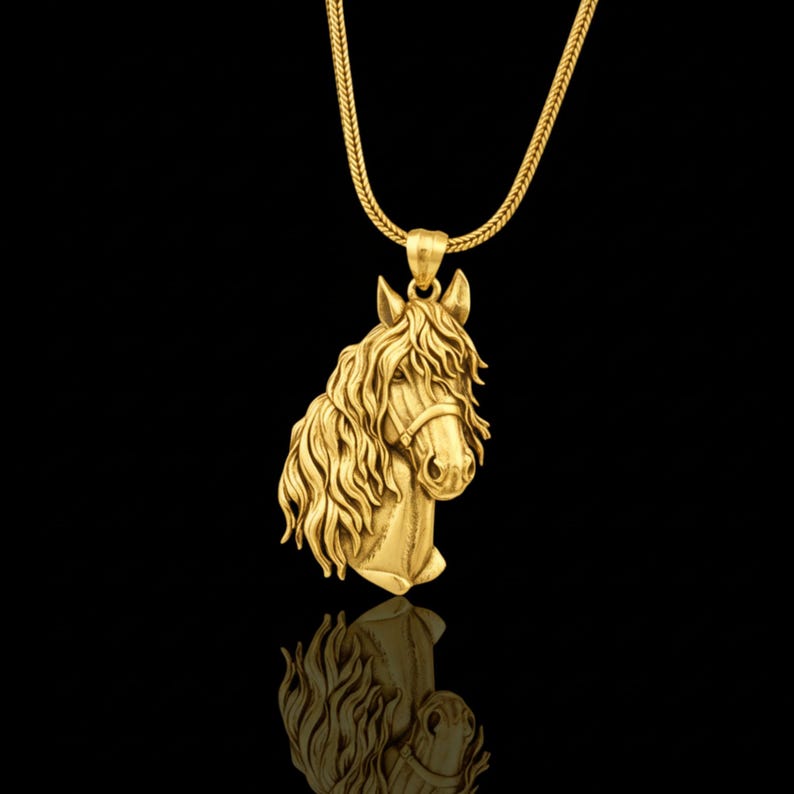 Puede incluir: Un collar con colgante dorado que presenta una cabeza de caballo detallada. El caballo tiene una melena fluida y lleva una brida. El colgante cuelga de una cadena dorada a juego. El fondo negro crea un contraste que resalta la joya.