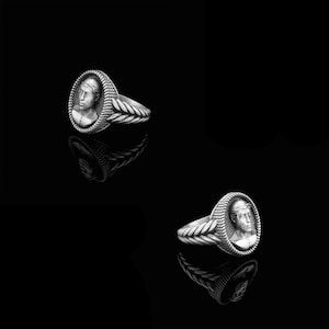 May include: Two silver rings with a detailed rope design on the band. Each ring features an oval-shaped cameo with a sculpted portrait of a person.