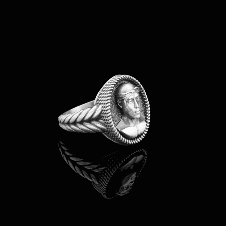 May include: A silver ring with a detailed rope design on the band and a cameo of a man's face in the center.