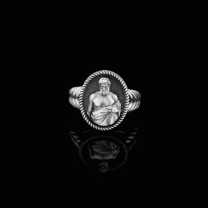 Puede incluir: Un anillo de plata con un camafeo ovalado detallado que presenta una imagen esculpida de un hombre con barba y una toga.