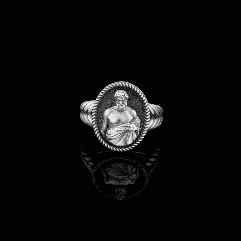 Puede incluir: Un anillo de plata con un camafeo ovalado detallado que presenta una imagen esculpida de un hombre con barba y una toga.