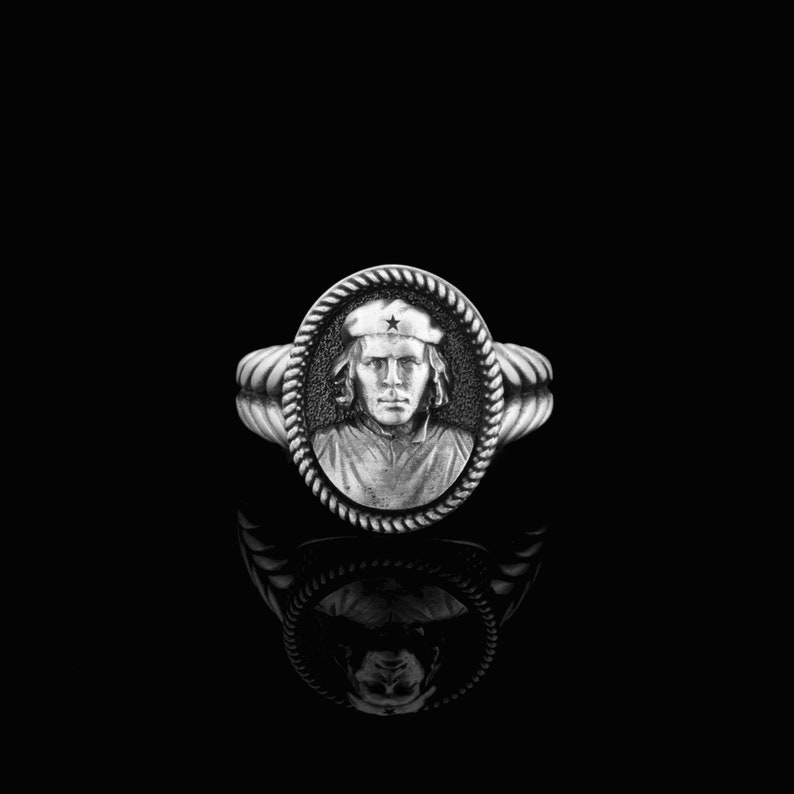 May include: A silver ring with a raised image of a man wearing a hat with a star on it. The ring is set in a rope-like band.