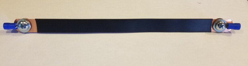 May include: A black electrical bus bar with copper terminals and blue insulated connectors. The bus bar is rectangular and has a bolt on each end. The terminals are secured with silver bolts.