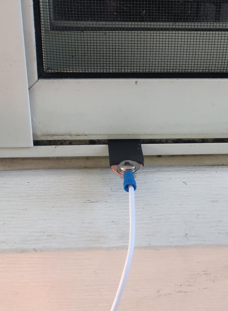 May include: A white window with a black screen and a white cable with a blue connector. The cable is connected to a metal piece secured with a screw and covered with black tape.