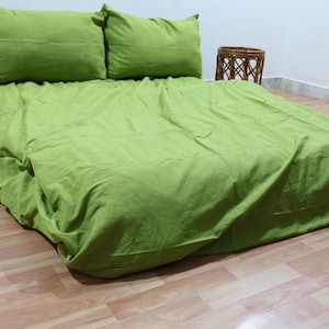 May include: A green bedspread with two matching pillowcases. The bedspread is made of a soft, textured fabric and has a simple, elegant design.