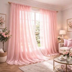 May include: Sheer pink curtains hang in front of a window, creating a soft, romantic ambiance. The curtains are made of a lightweight fabric that allows natural light to filter through. The curtains are hung on a gold rod.