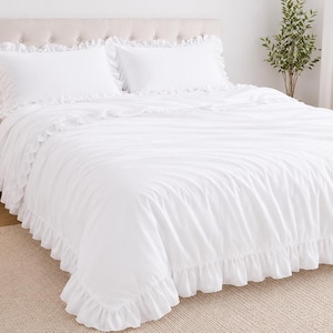 May include: A white bed featuring a tufted headboard, complemented by a white comforter and ruffled pillowcases. The bed is placed on a neutral rug, creating a calm and inviting bedroom setting.
