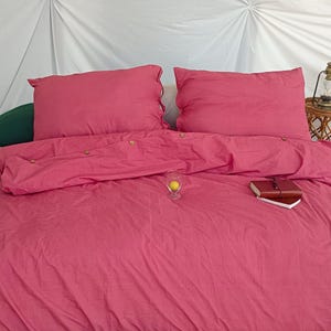 May include: A pink duvet cover with two matching pink pillowcases. The duvet cover has a button closure and is made of a soft, comfortable fabric.