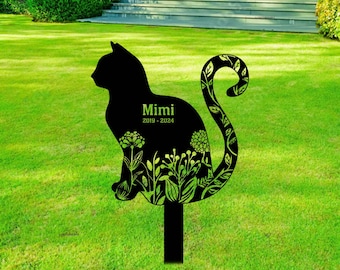 May include: Black metal silhouette of a cat with a floral design on its tail. The cat is sitting on a black metal stake. The cat's name, Mimi, and the dates 2019-2024 are inscribed on the silhouette.