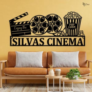 May include: Black metal cinema sign featuring a clapperboard, film reels, and a popcorn bucket. The sign reads "Enjoy the" above the clapperboard and "SILVAS CINEMA" below the film reels and popcorn.