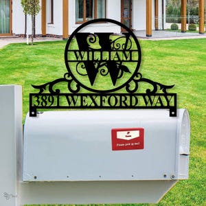 May include: Black metal address sign displaying the name "WILLIAM" and the address "3891 WEXFORD WAY". The sign is mounted above a white mailbox on a green lawn.
