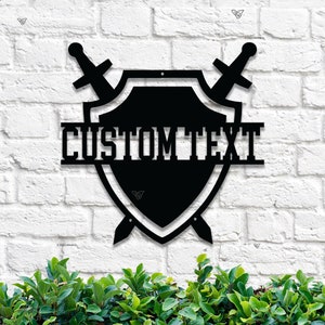 May include: Black metal shield with two swords crossed behind it. The shield has the text "CUSTOM TEXT" on the top.
